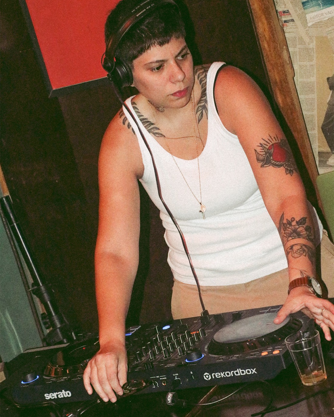 Helena Duppre tocando na cabine, com fones no pescoço, foto em preto e branco